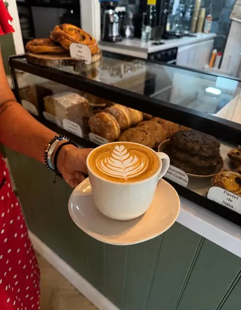 Freshly made latte with leaf-shaped latte art at Nook’s pastry counter